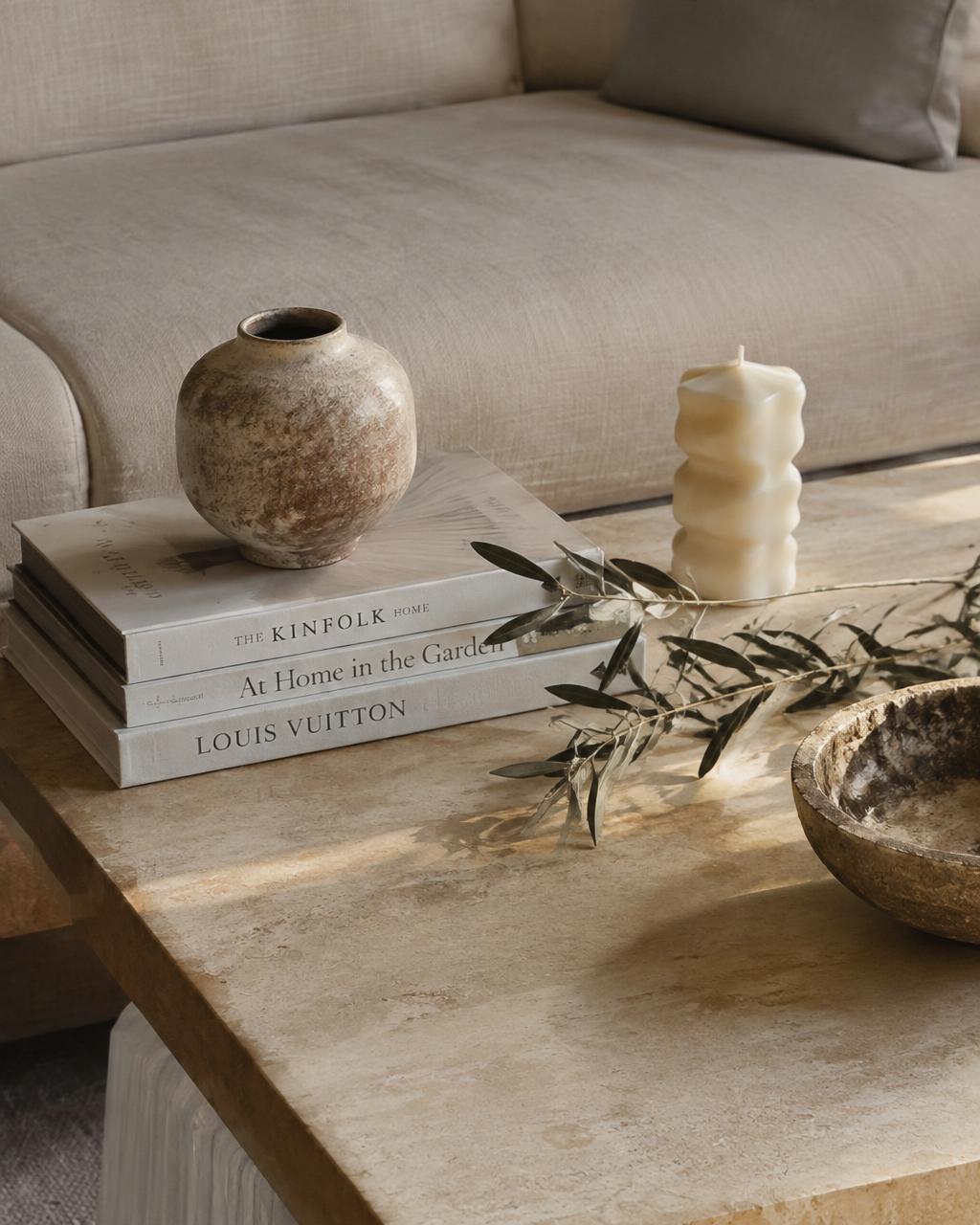 Travertine coffee table styled with books, stoneware vase and olive branch